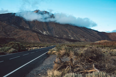 Scenic view of road by mountains against sky