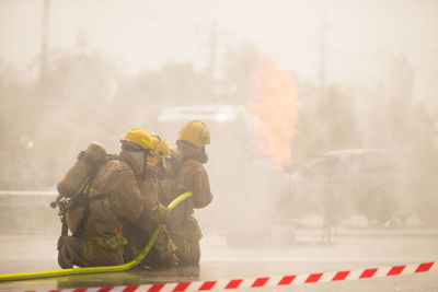 Firefighters spraying water on burning car in city