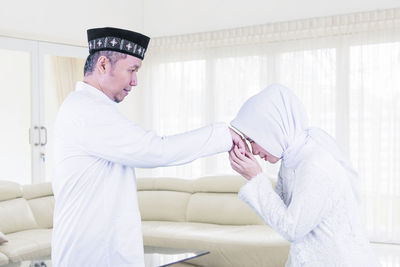 Side view of a young man standing at home
