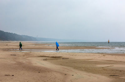 People walking at beach against sky