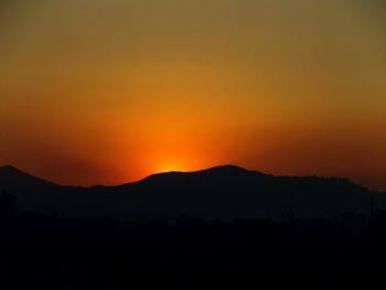 Scenic view of silhouette mountains against orange sky