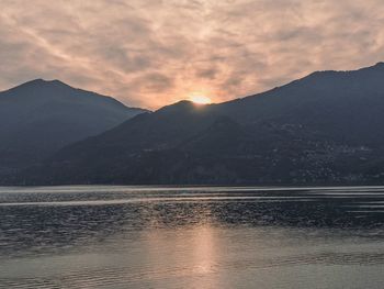 Scenic view of lake by mountains against sky during sunset