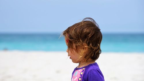 Side view of baby girl at beach against sky