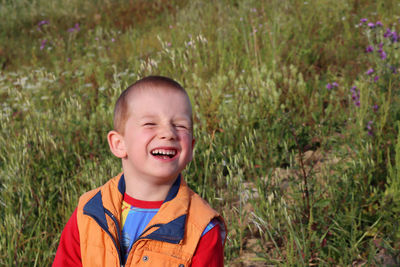 Portrait of a laughing blond boy in a field on a sunny day. joyful six year old boy.