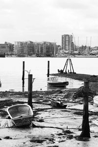 Boats moored on river in city against sky