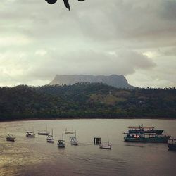 Boats in lake against cloudy sky