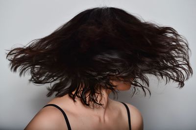 Close-up of woman tossing short hair against gray background