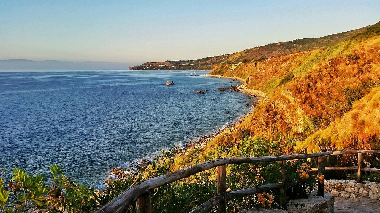 sea, water, clear sky, tranquil scene, tranquility, scenics, beach, beauty in nature, horizon over water, nature, mountain, coastline, shore, blue, idyllic, copy space, high angle view, sand, sunlight, plant