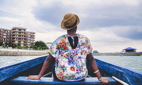 Man sitting on boat in river against sky