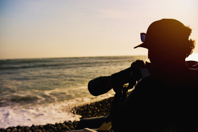 Surfing photographer in action. backlight during sunset with dramatic sky and reflection.