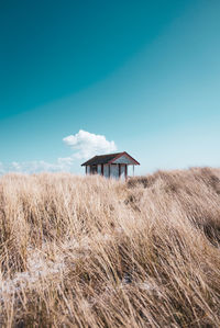 House on field against clear blue sky