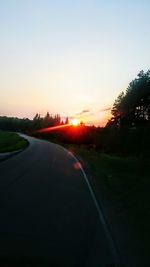 Road by landscape against clear sky during sunset