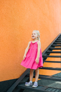 Full length of young woman standing against wall