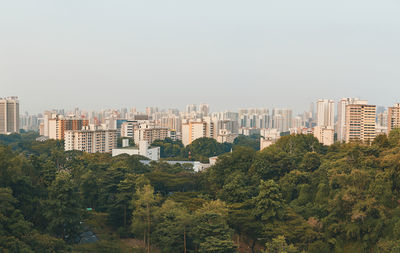 Trees and buildings against clear sky