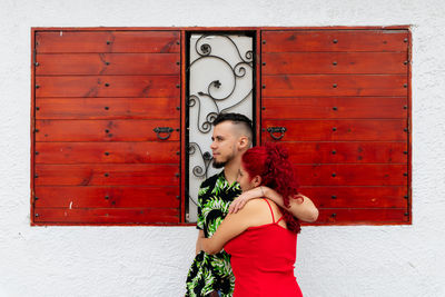 Portrait of woman standing against red door