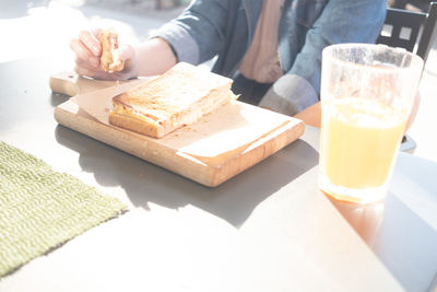 Midsection of woman eating sandwich at sidewalk cafe