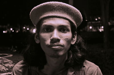 Portrait of young man wearing hat at night