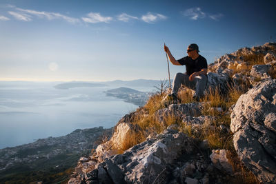 Man sitting on rock against mountains