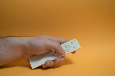 Close-up of hand holding text against orange background