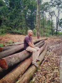 Full length of young man sitting in forest