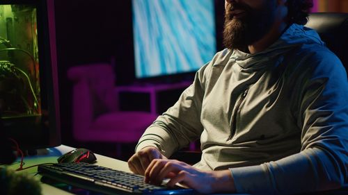 Rear view of man using laptop at home