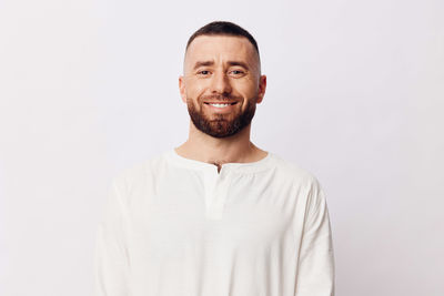 Portrait of young man standing against white background