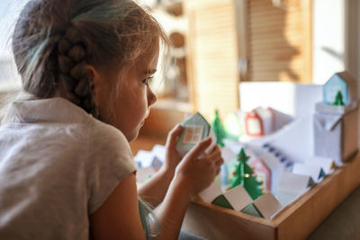 Origami advent calendar, paper craft. girl looking upon paper houses with number and paper tree