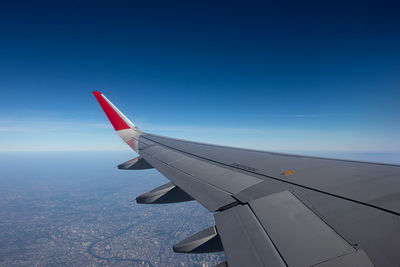 Airplane wing against clear blue sky