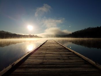 Pier over lake against sky during sunset