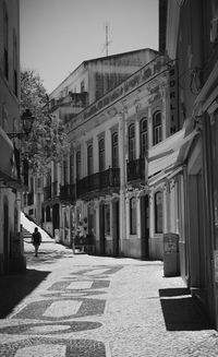 Man walking on footpath amidst buildings in city