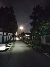 Illuminated street amidst buildings in city at night