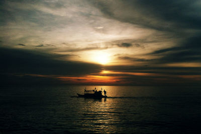 Silhouette boat in sea against sky during sunset