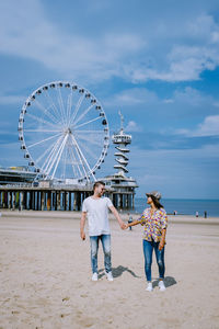 People at amusement park by sea against sky