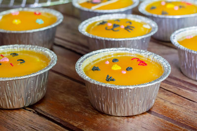 Close up minimal orange cake with butter cream in foil cup on wooden table. 