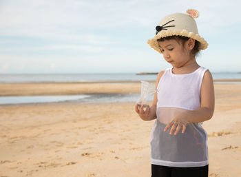 Full length of boy wearing hat while standing on beach