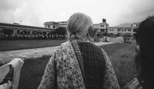 Rear view of woman standing in park against sky