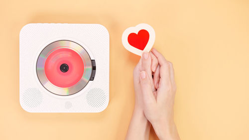 Cropped hand of woman holding heart shape against pink background