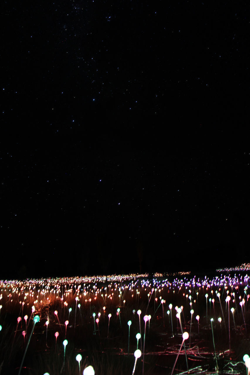 CROWD ON ILLUMINATED STREET AGAINST SKY