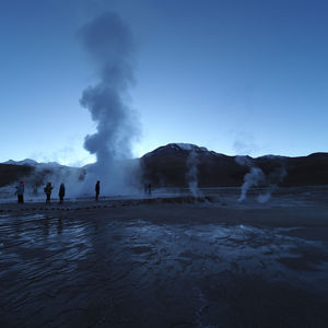 Smoke emitting from volcanic mountain against blue sky