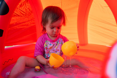 Cute baby girl playing while sitting in wading pool