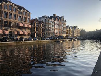 Canal by buildings against clear sky