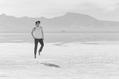 Young man levitating above salt flat during sunny day