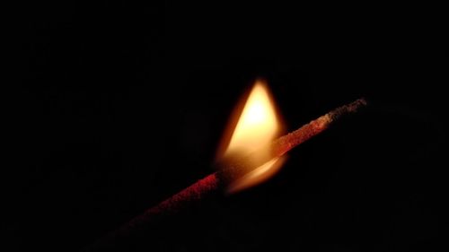 Close-up of lit candle in darkroom