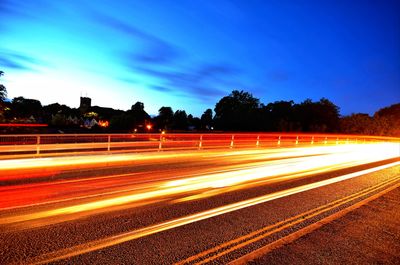 Light trails on road against sky at night