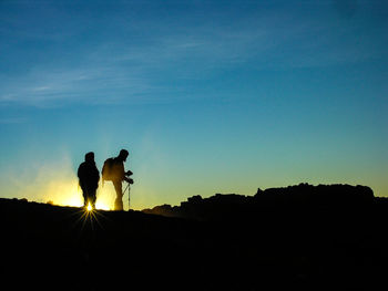 Silhouette couple standing against sky during sunset