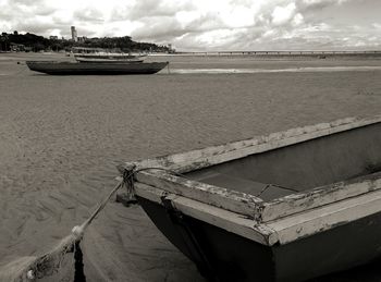 Boat moored on beach against sky