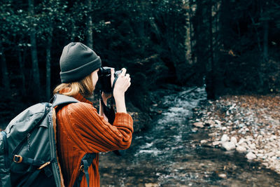 Rear view of woman photographing in forest