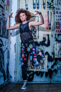 Portrait of young woman standing against graffiti wall