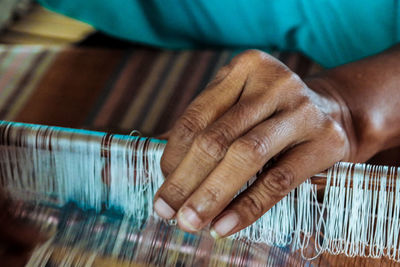 Cropped hand of woman with loom in workshop