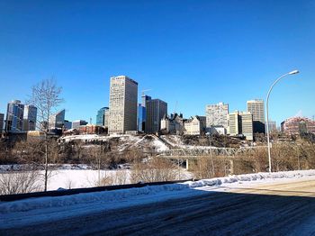 Buildings in city against clear blue sky during winter